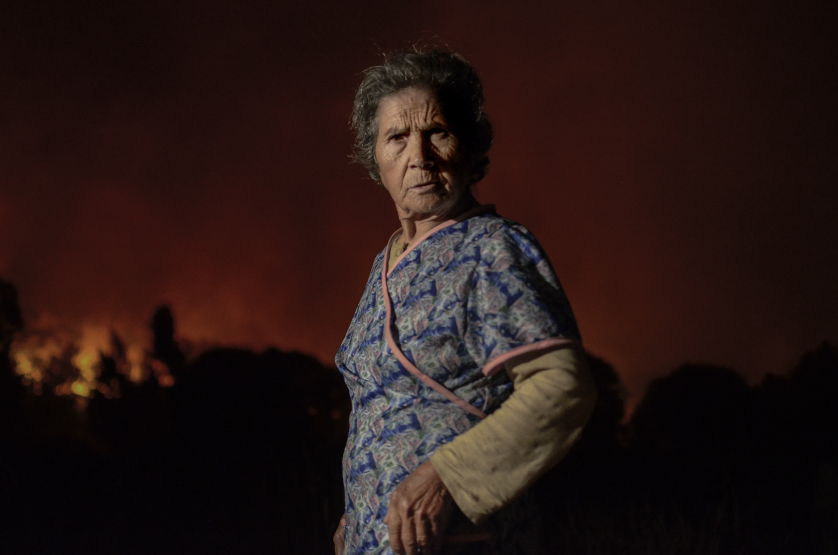 (ES) Maruja Rodríguez, 76, vecina de pueblo de Toubes, Ourense, noroeste de España, ante las llamas de un incendio forestal. Los incendios forestales que se producen en horario nocturno resultan más complicados de controlar por la imposibilidad de actuación de los medios aéreos.

(EN) Maruja Rodríguez, 76, stands in front of the flames of a forest fire near to the village of Toubes in municipality of San Cristovo de Cea, Ourense, northwestern Spain. Forest fires that happened at night are more difficult to control due to the impossibility of action by the aerial means.